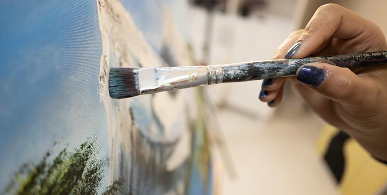 A woman painting onto a canvas